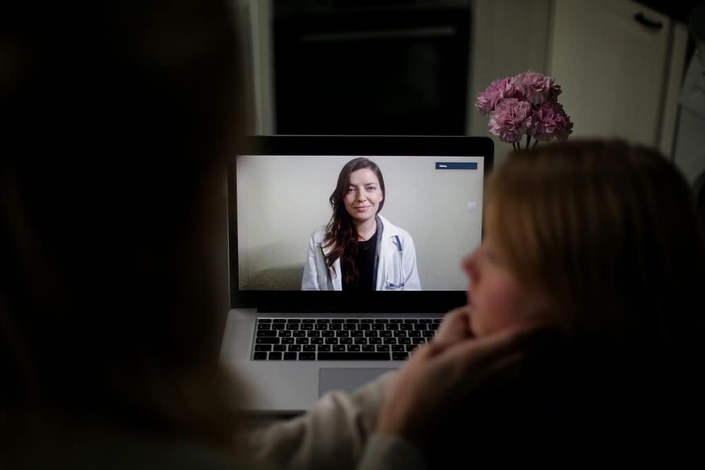 A doctor appears on a laptop screen during an online medical consultation at home, illustrating Sakura Skin's telehealth evaluation process for weight loss patients in Linden and Holly Michigan
