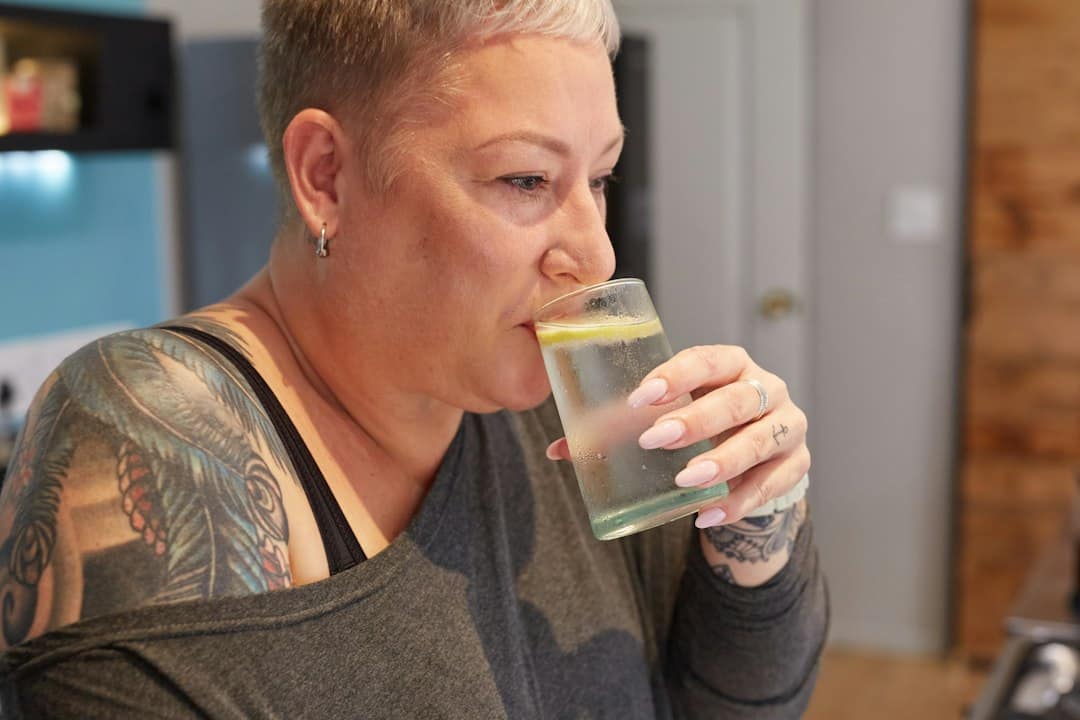 Woman sipping water, one simple way to ease tirzepatide nausea