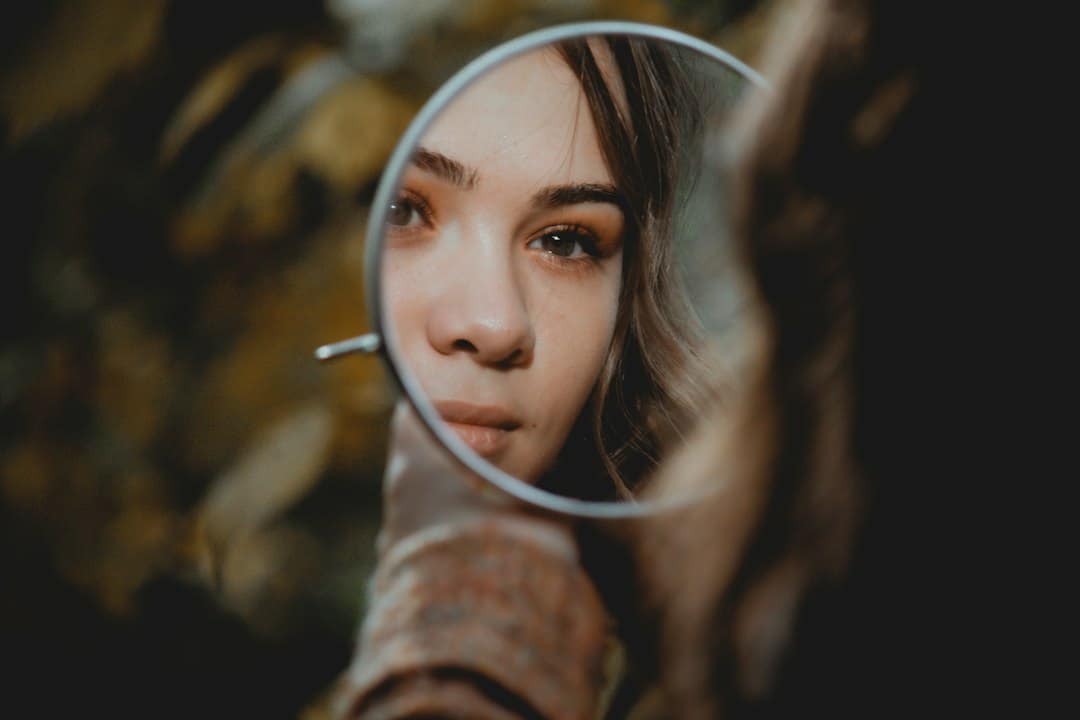 Woman checking her results in a hand mirror, wondering how long Botox lasts